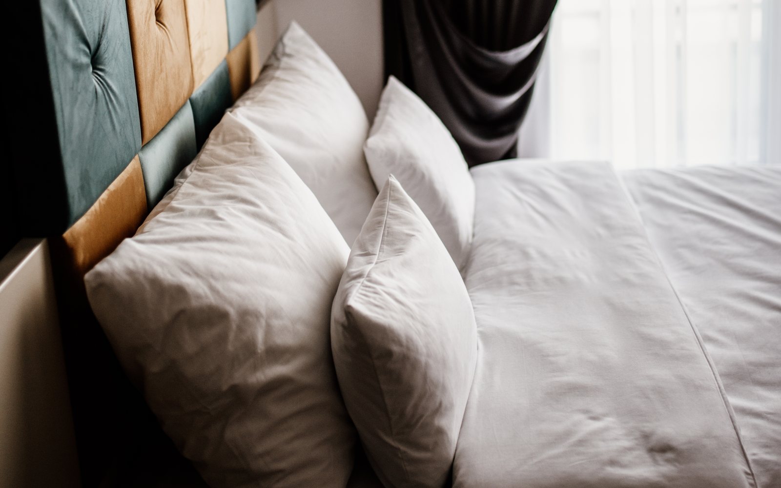 Lit aux draps et oreillers blancs près d'une fenêtre lumineuse